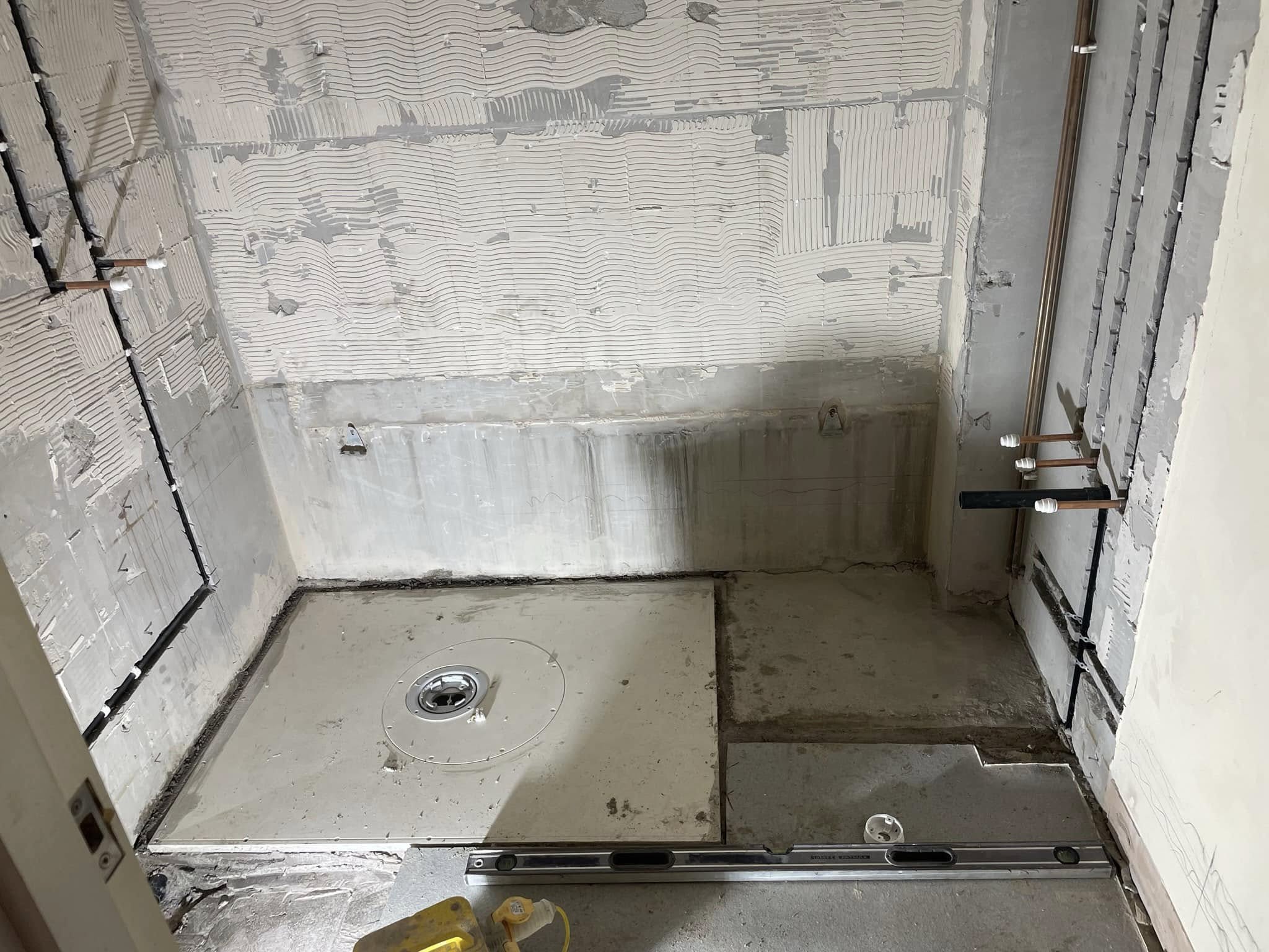 Disabled wet room before — stripped back to bare walls and floor