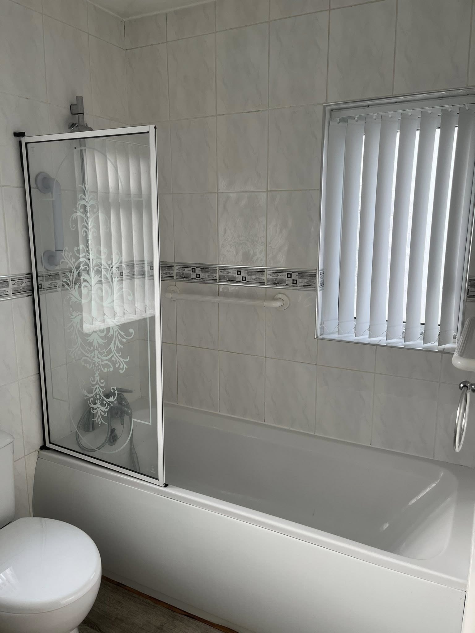 Mobility bathroom before — dated white tiles, glass shower screen