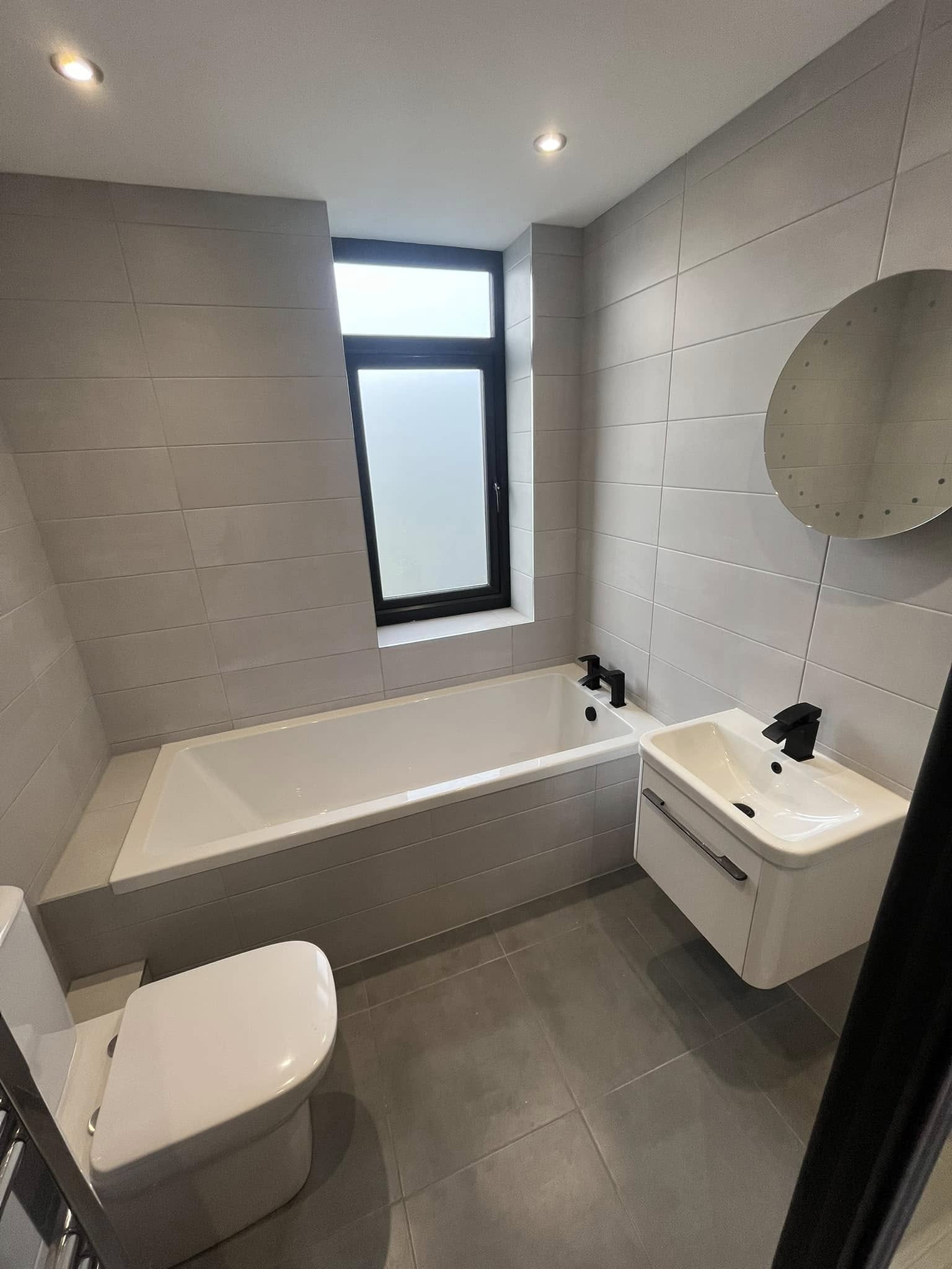 Sleek grey bathroom with floating bath and modern fittings